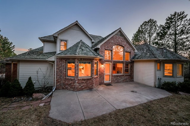 back of house featuring brick siding and a patio area