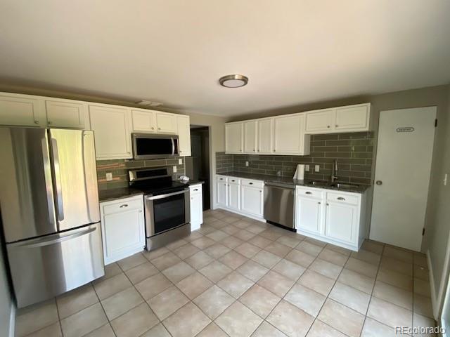 217 Ford St, Golden, CO 80403 - kitchen with appliances with stainless steel finishes, dark countertops, backsplash, and white cabinetry