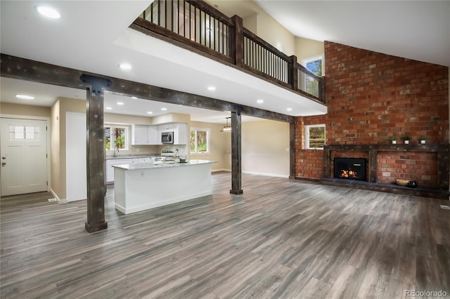 595 Wintery Cir, Colorado Springs, CO 80919 - unfurnished living room with dark wood-style flooring, baseboards, a brick fireplace, lofted ceiling, and recessed lighting