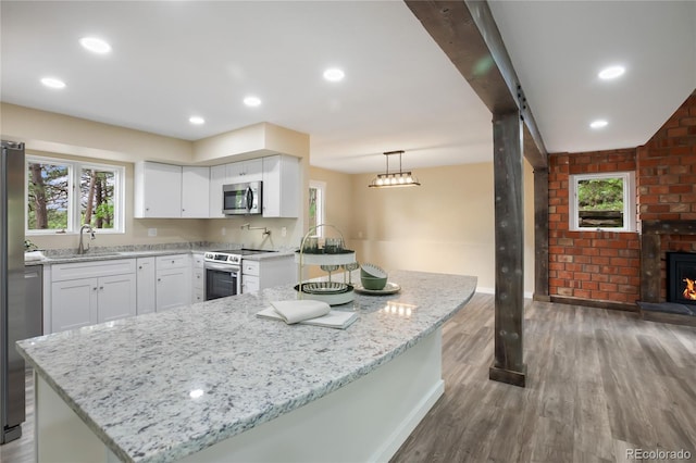 595 Wintery Cir, Colorado Springs, CO 80919 - kitchen with stainless steel appliances, a sink, wood finished floors, light stone countertops, and white cabinetry
