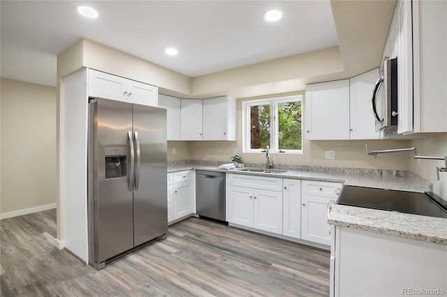595 Wintery Cir, Colorado Springs, CO 80919 - kitchen featuring stainless steel appliances, a sink, white cabinets, light stone counters, and recessed lighting