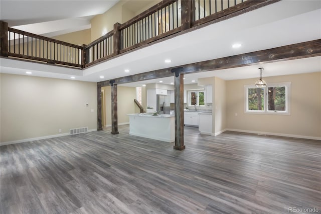 595 Wintery Cir, Colorado Springs, CO 80919 - unfurnished living room with a barn door, a towering ceiling, baseboards, dark wood finished floors, and recessed lighting
