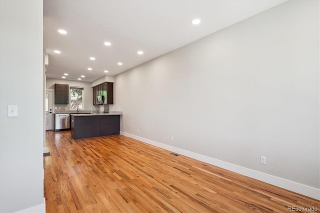 unfurnished living room with recessed lighting, light wood-style floors, baseboards, and a sink