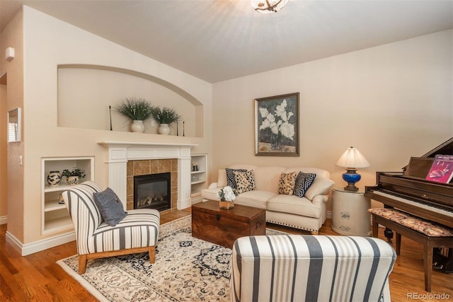 9165 Kornbrust Dr, Lone Tree, CO 80124 - living room with wood finished floors, built in shelves, baseboards, a tile fireplace, and vaulted ceiling