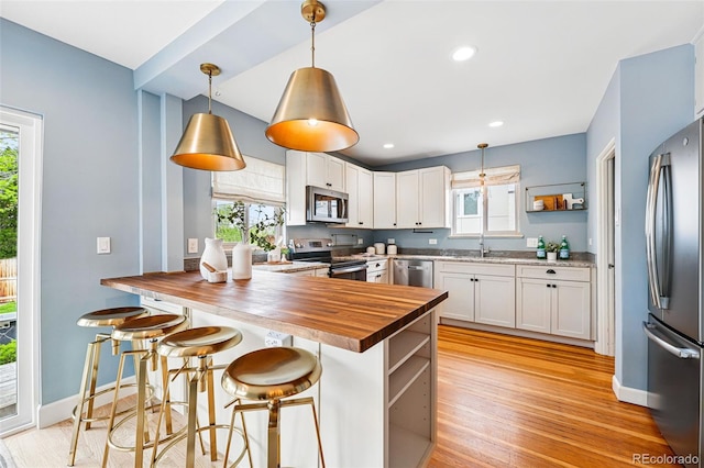 kitchen with stainless steel appliances, butcher block counters, open shelves, white cabinetry, and recessed lighting