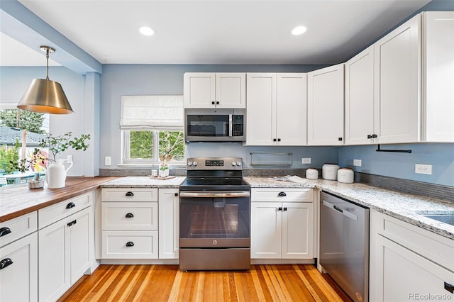 kitchen with stainless steel appliances, white cabinetry, light wood-style flooring, and recessed lighting