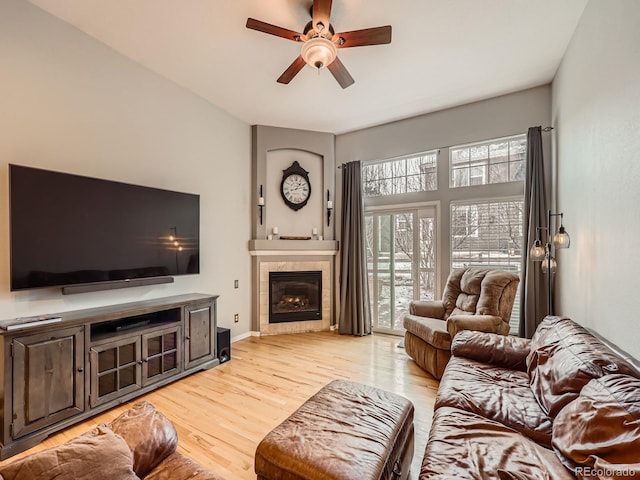 living room featuring ceiling fan, a fireplace, and light wood-type flooring