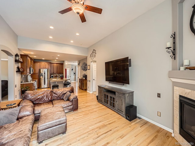 living room with light hardwood / wood-style flooring, a fireplace, and ceiling fan