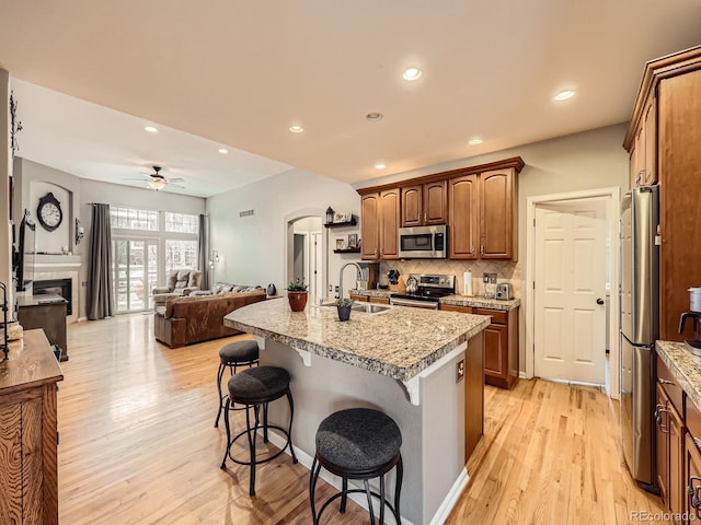 kitchen with appliances with stainless steel finishes, sink, backsplash, a kitchen breakfast bar, and a kitchen island with sink