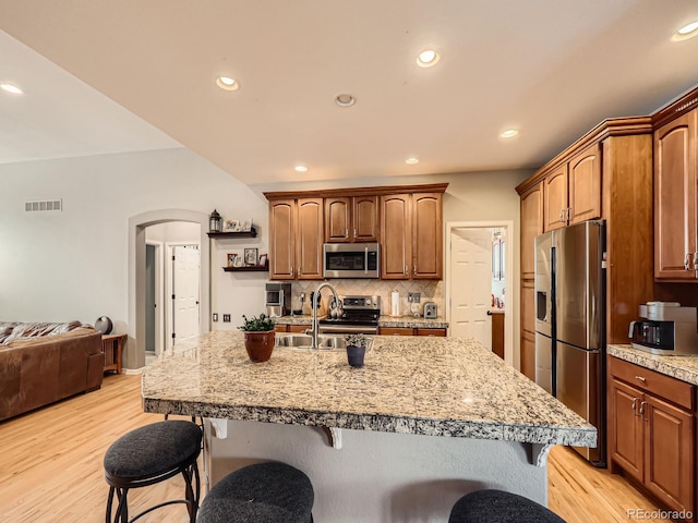 kitchen with appliances with stainless steel finishes, sink, a center island with sink, and a kitchen bar