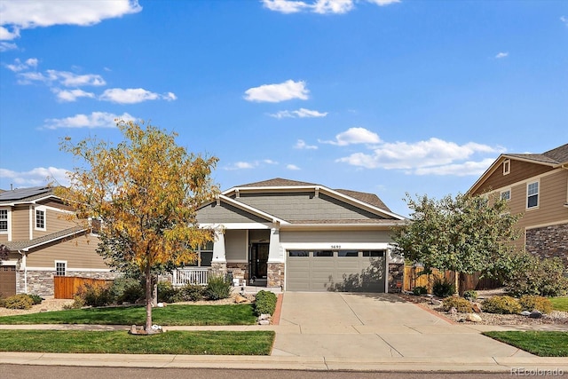 craftsman-style home featuring a garage, covered porch, and a front lawn