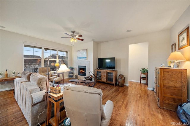 living room featuring a fireplace, ceiling fan, and light hardwood / wood-style flooring