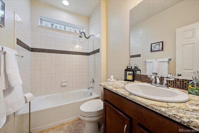 full bathroom featuring vanity, tiled shower / bath combo, and toilet