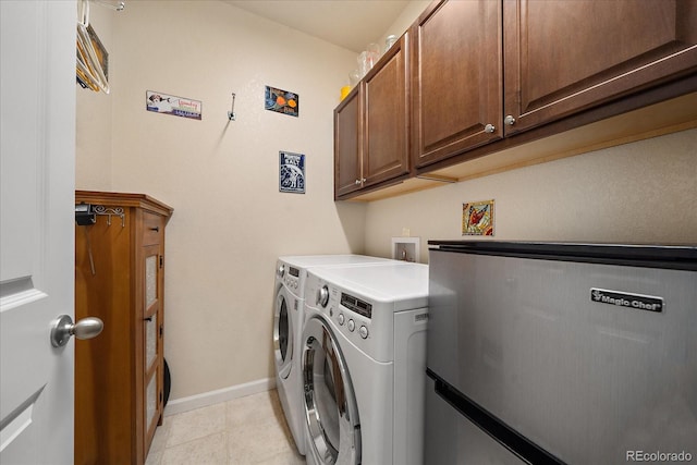 laundry room featuring washing machine and clothes dryer, light tile patterned flooring, and cabinets