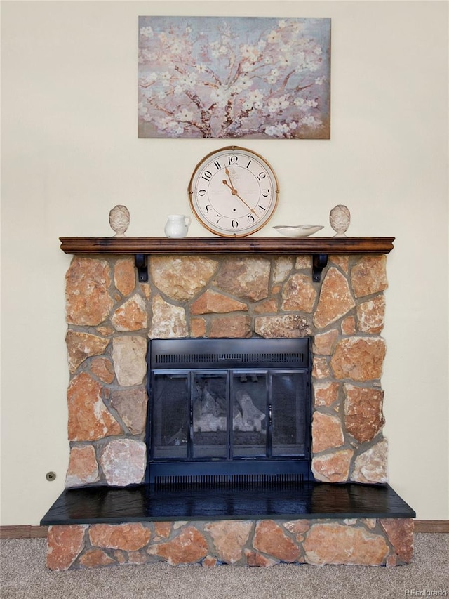 interior details with baseboards, carpet floors, and a stone fireplace