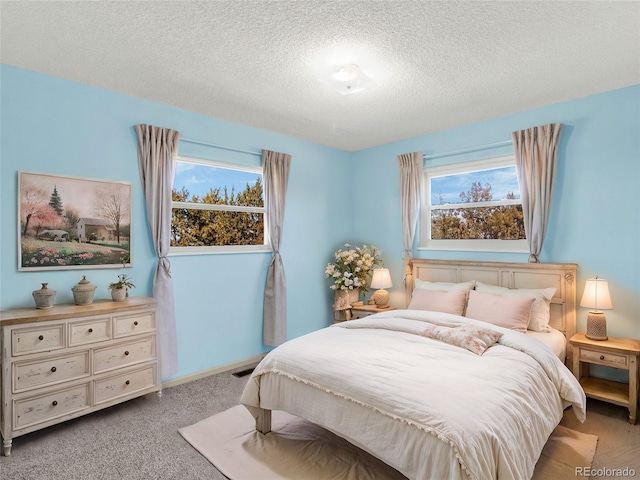 bedroom featuring light colored carpet, a textured ceiling, and baseboards