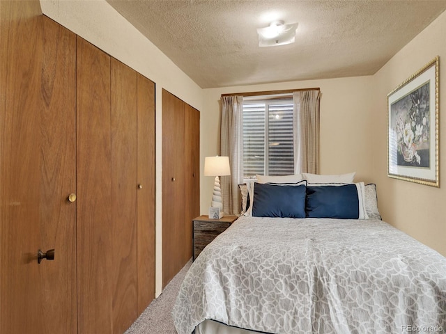 carpeted bedroom with multiple closets and a textured ceiling