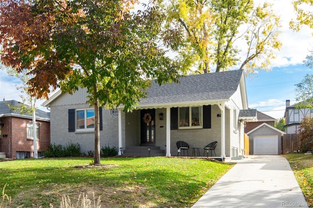 view of front of home with a garage, a front yard, brick siding, and an outdoor structure