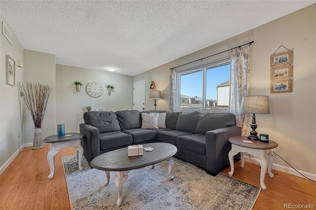 living area with baseboards, visible vents, a textured ceiling, and wood finished floors