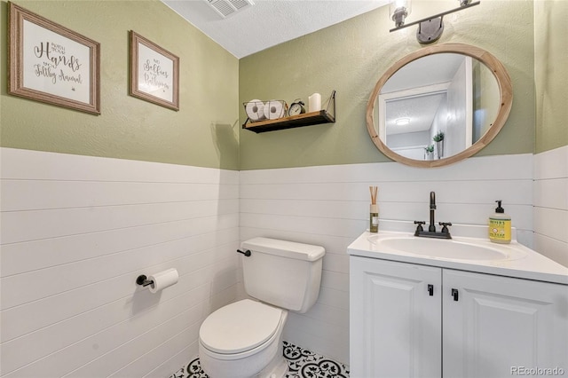 bathroom with vanity, visible vents, toilet, and wainscoting