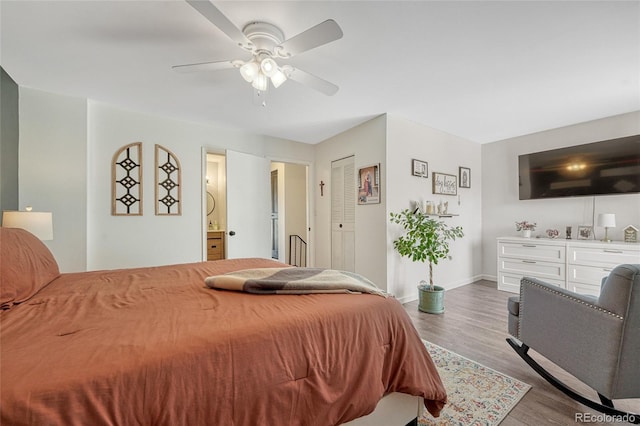 bedroom with a ceiling fan, ensuite bath, baseboards, and wood finished floors