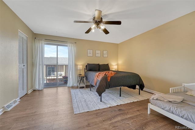 bedroom featuring access to exterior, baseboards, visible vents, and wood finished floors