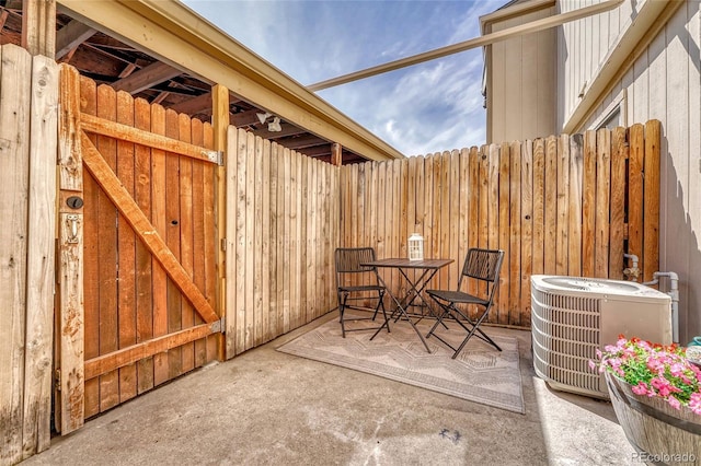 view of patio with outdoor dining area, central AC unit, and fence