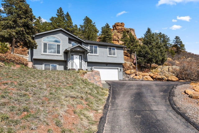 bi-level home with aphalt driveway, stucco siding, and a garage