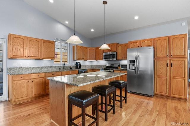 kitchen featuring a center island, stone counters, stainless steel appliances, and light wood-type flooring