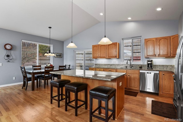 kitchen featuring a breakfast bar, stone countertops, a center island, light wood-style floors, and dishwasher