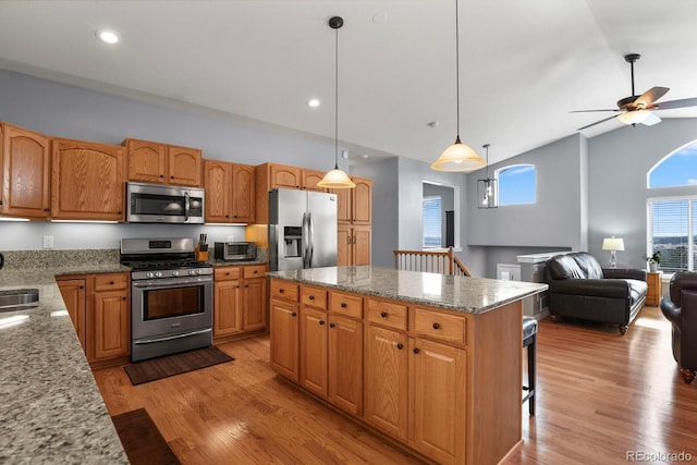 kitchen with light stone counters, stainless steel appliances, open floor plan, and light wood-style flooring