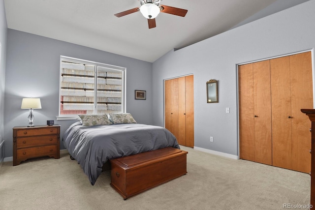 bedroom with baseboards, ceiling fan, vaulted ceiling, multiple closets, and light carpet