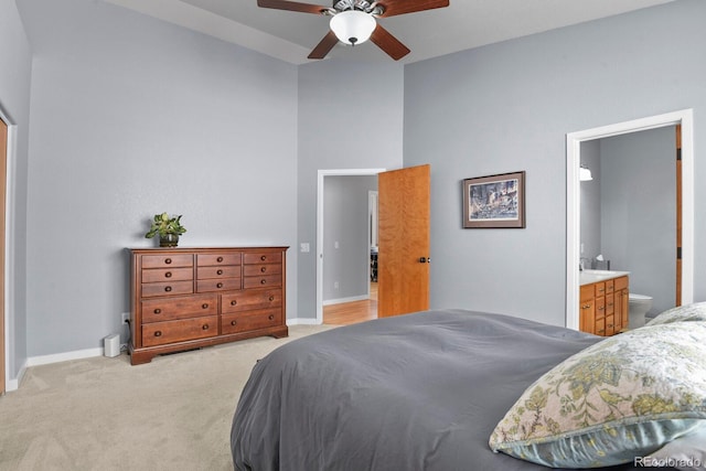 bedroom featuring baseboards, light colored carpet, ceiling fan, and ensuite bathroom