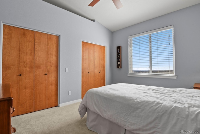 bedroom with two closets, baseboards, ceiling fan, carpet, and lofted ceiling