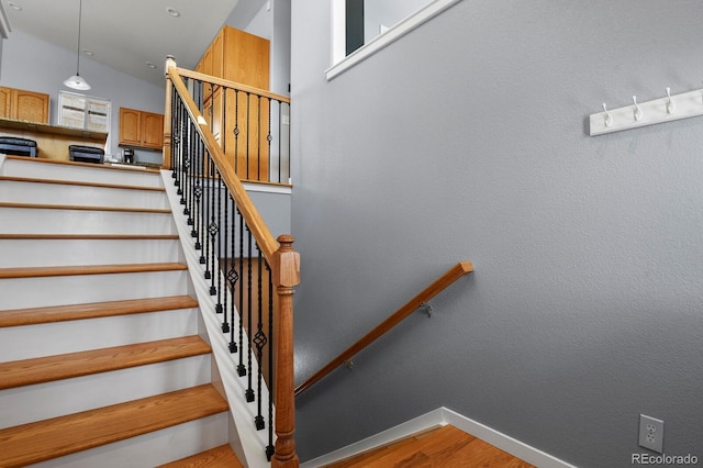 staircase with baseboards, lofted ceiling, and wood finished floors