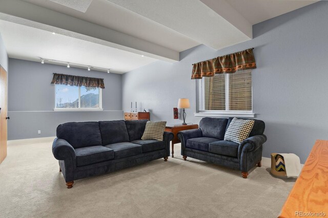 carpeted living room featuring beamed ceiling, rail lighting, and baseboards