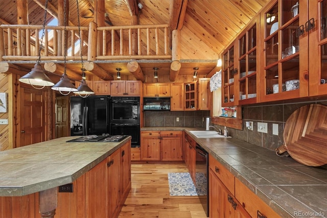 kitchen featuring light wood-type flooring, tile countertops, a sink, and black appliances