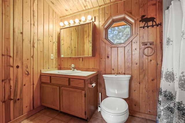 bathroom with toilet, tile patterned floors, wood walls, and vanity