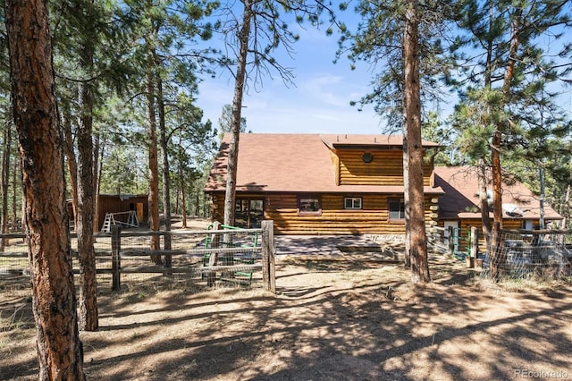 back of house featuring log siding and fence
