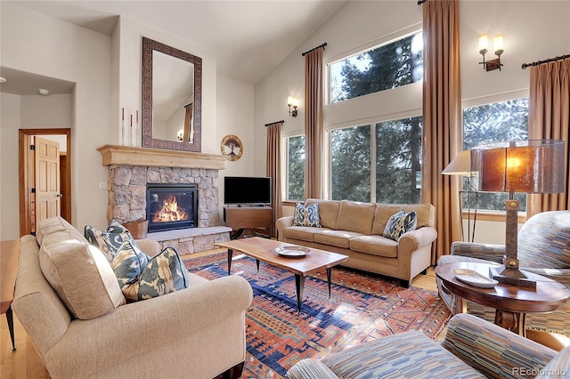 living room with lofted ceiling, a stone fireplace, a healthy amount of sunlight, and hardwood / wood-style flooring