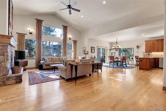 living room featuring ceiling fan with notable chandelier, a wealth of natural light, high vaulted ceiling, and light hardwood / wood-style flooring