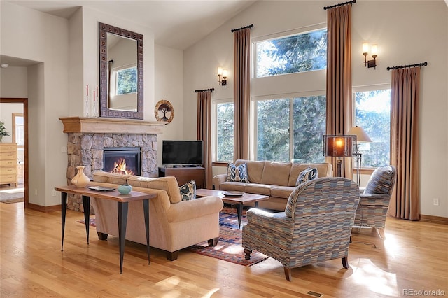 living room featuring a fireplace, high vaulted ceiling, and light hardwood / wood-style flooring