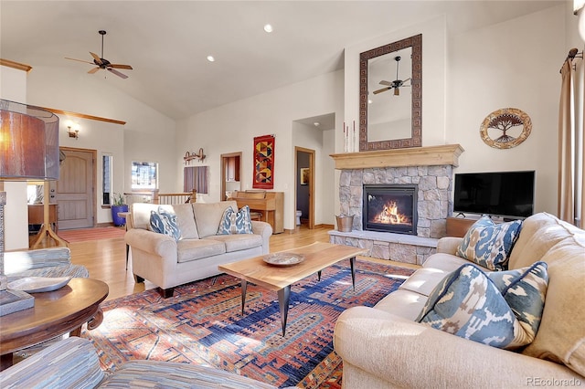 living room with ceiling fan, a fireplace, high vaulted ceiling, and light wood-type flooring