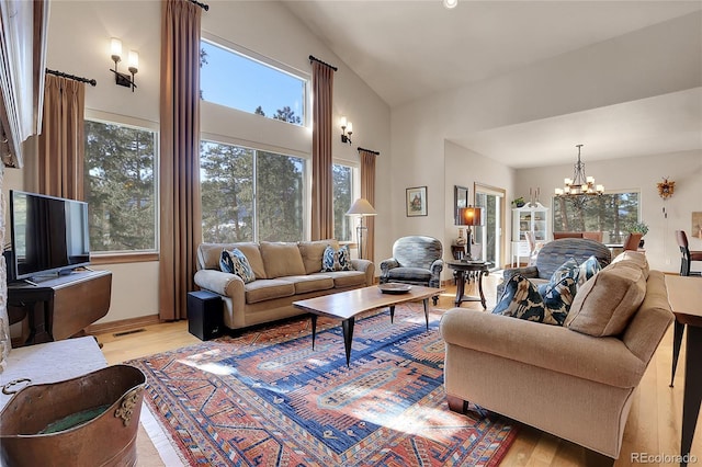 living room with lofted ceiling, light hardwood / wood-style flooring, and a notable chandelier