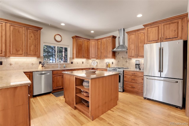 kitchen with appliances with stainless steel finishes, a center island, light hardwood / wood-style flooring, and wall chimney range hood