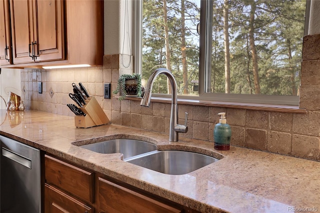 kitchen with tasteful backsplash, sink, light stone counters, and stainless steel dishwasher