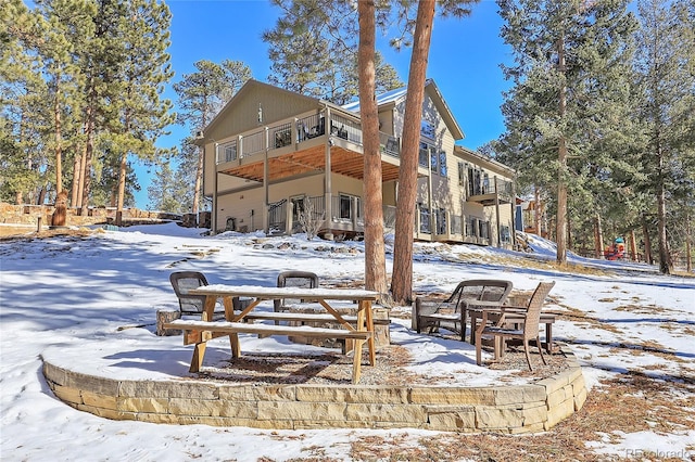 snow covered back of property with a balcony