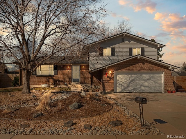 tri-level home with a garage, driveway, and brick siding