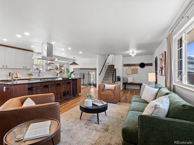 living area featuring light wood-style flooring, recessed lighting, and stairway