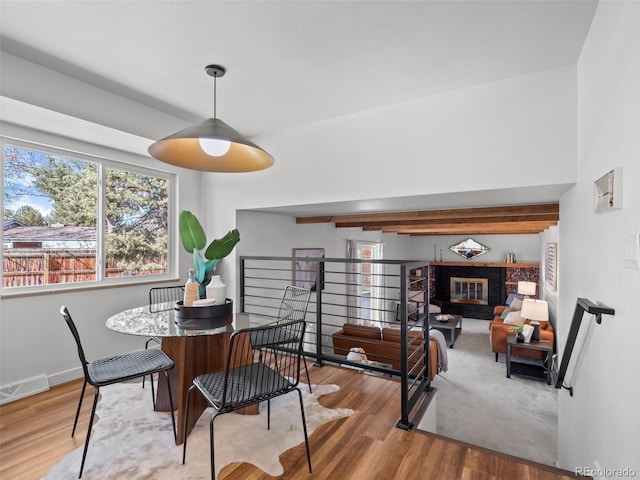 dining space featuring a glass covered fireplace, wood finished floors, visible vents, and baseboards